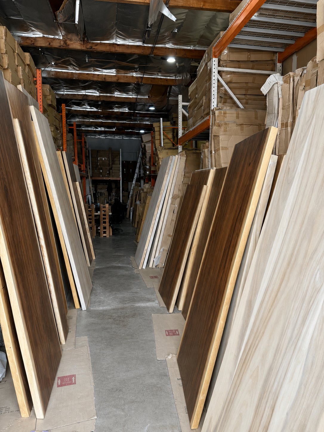 Rows of natural and bleached live-edge tabletops available to compare inside the HEFT Home Irvine warehouse